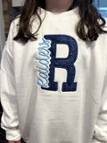 White sweatshirt with navy glitter applique letter R and Raiders embroidered in light blue script